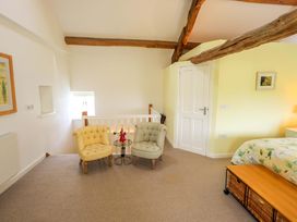 A bedroom with two armchairs and a side table at Kestrel Cottage Beckside near Cartmel