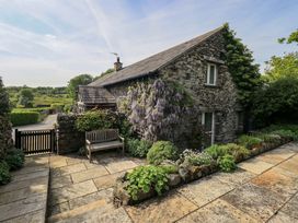 A stone house with garden and bench at Kestrel Cottage in Beckside near Cartmel