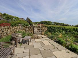 A garden with seating area and stone wall at Kestrel Cottage Beckside near Cartmel