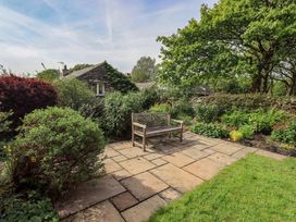 A garden with a stone pathway and a wooden bench at Kestrel Cottage Beckside near Cartmel