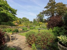 A garden with flowers and a bench at Kestrel Cottage Beckside near Cartmel