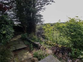 A garden with a stone pathway and trees at Kestrel Cottage in Beckside near Cartmel