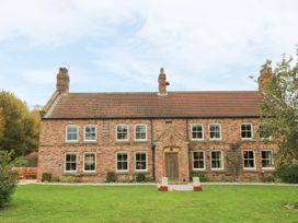 A brick house with multiple windows and a wooden front door with a tiled roof and green lawn at Copmanthorpe Hall in Copmanthorpe