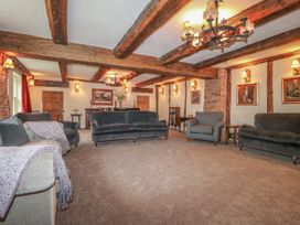 A sitting room with exposed wooden beams on the ceiling and walls with sofas and armchairs at Copmanthorpe Hall in Copmanthorpe