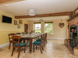 A dining room with a wooden table, chairs with teal cushions, a fireplace, and windows at Copmanthorpe Hall in Copmanthorpe