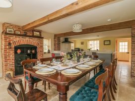 A dining area with a large wooden table set for eight people with wooden chairs and blue cushions in a room with exposed wooden beams and a brick fireplace at Copmanthorpe Hall in Copmanthorpe