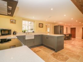A kitchen with grey cabinets a white countertop a window with blinds a black stove a microwave a kettle a stainless steel refrigerator and a dining table with chairs at Copmanthorpe Hall in Copmanthorpe
