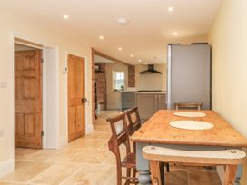 A kitchen with wooden table and chairs wooden doors and tiled floor at Copmanthorpe Hall in Copmanthorpe