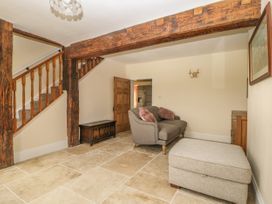 A sitting area with a gray loveseat and ottoman near a wooden staircase and exposed wooden beams at Copmanthorpe Hall in Copmanthorpe