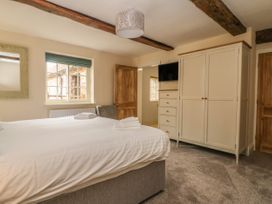 A bedroom with a bed folded towels a wardrobe a chest of drawers a mounted television a window and wooden doors at Copmanthorpe Hall in Copmanthorpe