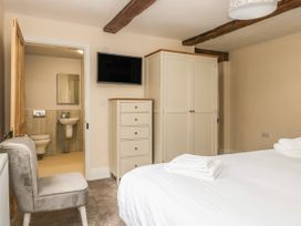 A bedroom with a bed folded towels chair wardrobe chest of drawers and a wall mounted television at Copmanthorpe Hall in Copmanthorpe