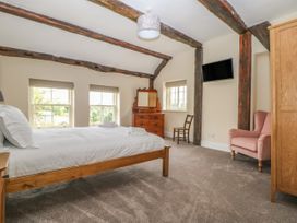 A bedroom with a bed a dresser a chair a pink armchair and a wall-mounted tv at Copmanthorpe Hall in Copmanthorpe