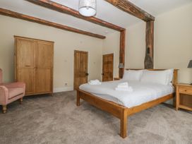 A bedroom with a wooden bed and wardrobe and a pink armchair at Copmanthorpe Hall in Copmanthorpe
