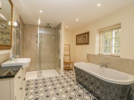 A bathroom with a shower area a bathtub a sink a mirror a wooden chair and a window at Copmanthorpe Hall in Copmanthorpe