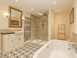 A bathroom with a bathtub sink mirror shower and towel rack at Copmanthorpe Hall in Copmanthorpe