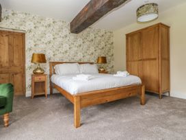 A bedroom with a wooden double bed two bedside tables with gold lamps a wooden wardrobe and floral wallpaper at Copmanthorpe Hall in Copmanthorpe