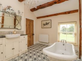 A bathroom with a freestanding bathtub a wooden door patterned floor tiles and a large mirror above a sink at Copmanthorpe Hall in Copmanthorpe