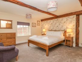 A bedroom with a wooden bed and nightstands beside floral wallpaper at Copmanthorpe Hall in Copmanthorpe