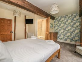A bedroom with a wooden bed white linens wooden furniture floral wallpaper and an en suite bathroom at Copmanthorpe Hall in Copmanthorpe