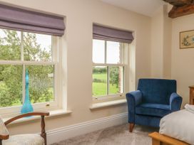A room with two windows with purple blinds a blue armchair a patterned chair and a bed at Copmanthorpe Hall in Copmanthorpe