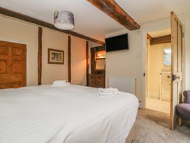 A bedroom with a bed white linens folded towels a wall-mounted television wooden beams and an open door leading to a bathroom at Copmanthorpe Hall in Copmanthorpe