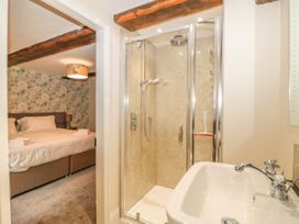 A bathroom with a shower and sink next to a bedroom with a bed and floral wallpaper at Copmanthorpe Hall in Copmanthorpe