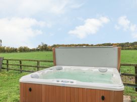 An outdoor hot tub with water in a grassy area with a wooden fence and trees in the background at Copmanthorpe Hall in Copmanthorpe