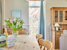 A dining room with a wooden table and flowers at East Wing in Crewkerne