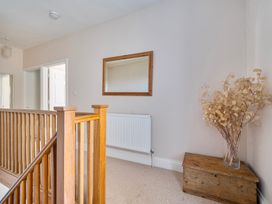 A hallway with a staircase, mirror, radiator, and a decorative plant at East Wing in Crewkerne
