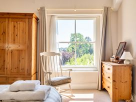 A bedroom with a wardrobe and a window at East Wing in Crewkerne