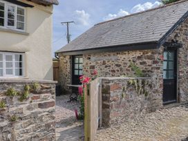 An outdoor area with a stone wall and a table at The Old Workshop in Knowstone