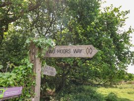 A wooden signpost for Two Moors Way with surrounding greenery at The Old Workshop in Knowstone