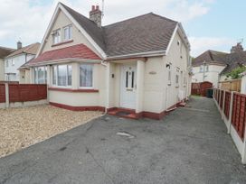 An exterior view of a detached house with a driveway and a pebble garden area at Maesdu Cottage in Llandudno