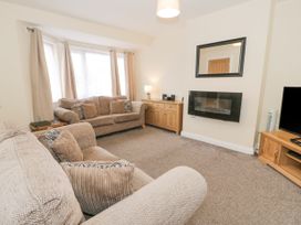 A living room with two sofas a wooden cabinet a wall-mounted fireplace a mirror and a television at Maesdu Cottage in Llandudno