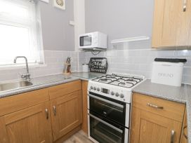 A kitchen corner with a gas stove oven microwave knife block bread box and sink at Maesdu Cottage in Llandudno