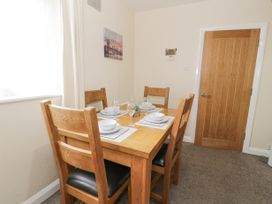 A dining room with a wooden table set for four and wooden chairs at Maesdu Cottage in Llandudno