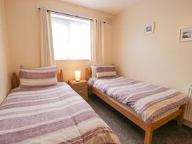A bedroom with two single beds and a nightstand with a lamp between them at Maesdu Cottage in Llandudno