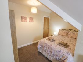 A bedroom with a double bed covered in butterfly patterned bedding and two folded towels on top at Maesdu Cottage in Llandudno
