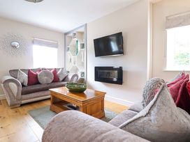 A living room with a sofa, coffee table and television at Moelfre Cottage Llanbedr