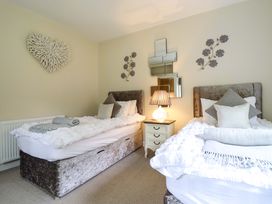 A bedroom with two beds and a lamp on a bedside table at Moelfre Cottage Llanbedr