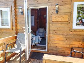 A wooden cabin entrance with an open door two chairs and a sign reading Aurora Skies at Aurora Skies in Cresswell near Morpeth