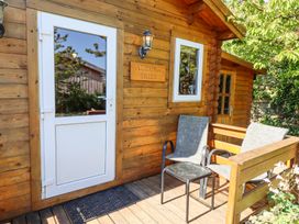 A wooden cabin entrance with a white door two chairs and a small table on the porch at Aurora Skies in Cresswell near Morpeth