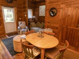 A wooden dining table with four chairs in a living room with a sofa armchair and door at Aurora Skies in Cresswell near Morpeth