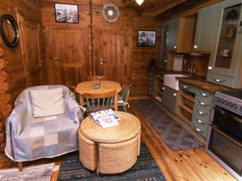 A wooden kitchen and dining area with a round table four chairs armchair and wicker coffee table at Aurora Skies in Cresswell near Morpeth