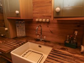 A kitchen sink area with wooden countertop and cabinets and a sign with beach house rules at Aurora Skies in Cresswell near Morpeth