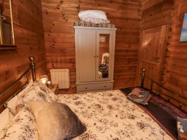 A bedroom with a bed covered with floral bedding a wardrobe with a mirror and wooden walls at Aurora Skies in Cresswell near Morpeth