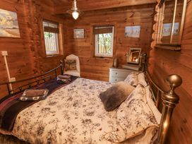 A bedroom with a floral bedspread two windows a chair a dresser and wooden walls at Aurora Skies in Cresswell near Morpeth