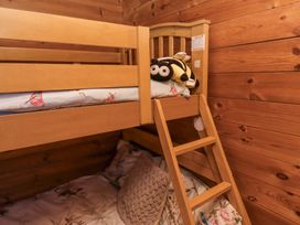 A wooden bunk bed with a ladder and floral bedding in a wooden room at Aurora Skies in Cresswell near Morpeth