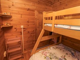 A wooden bedroom with bunk beds floral bed covers a pink metal shelving unit and wooden shelves at Aurora Skies in Cresswell near Morpeth