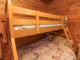 A bunk bed with floral bedding and a ladder in a wooden room at Aurora Skies in Cresswell near Morpeth